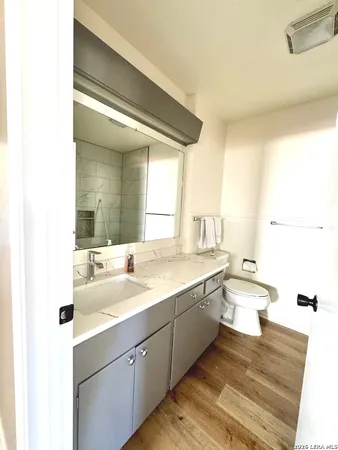 a bathroom with a granite countertop sink a toilet and a large mirror