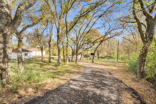 a view of a white house with a big yard and large trees