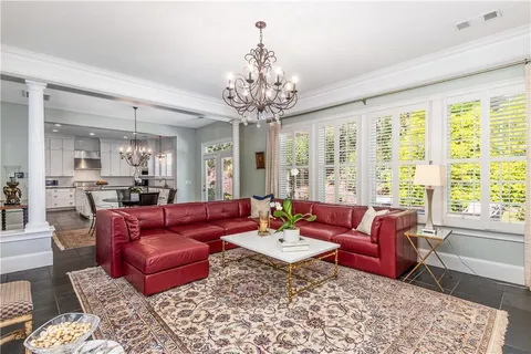 a living room with furniture large windows and wooden floor