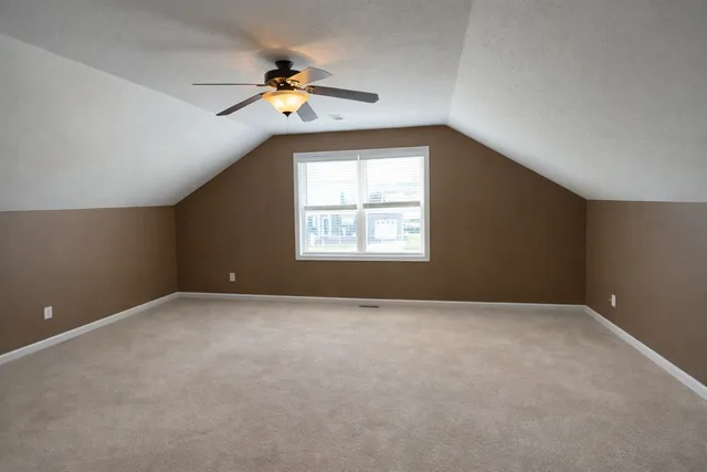an empty room with windows and chandelier fan