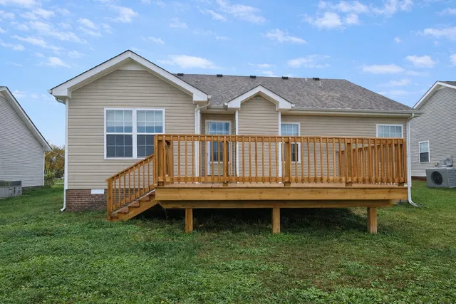 a view of a house with a wooden deck and a yard
