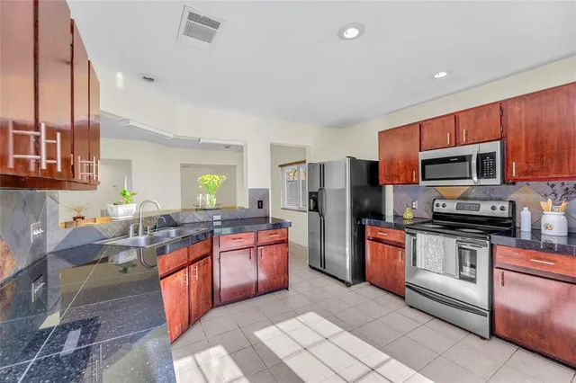 a kitchen with stainless steel appliances granite countertop a stove top oven a sink dishwasher a refrigerator and cabinets with wooden floor