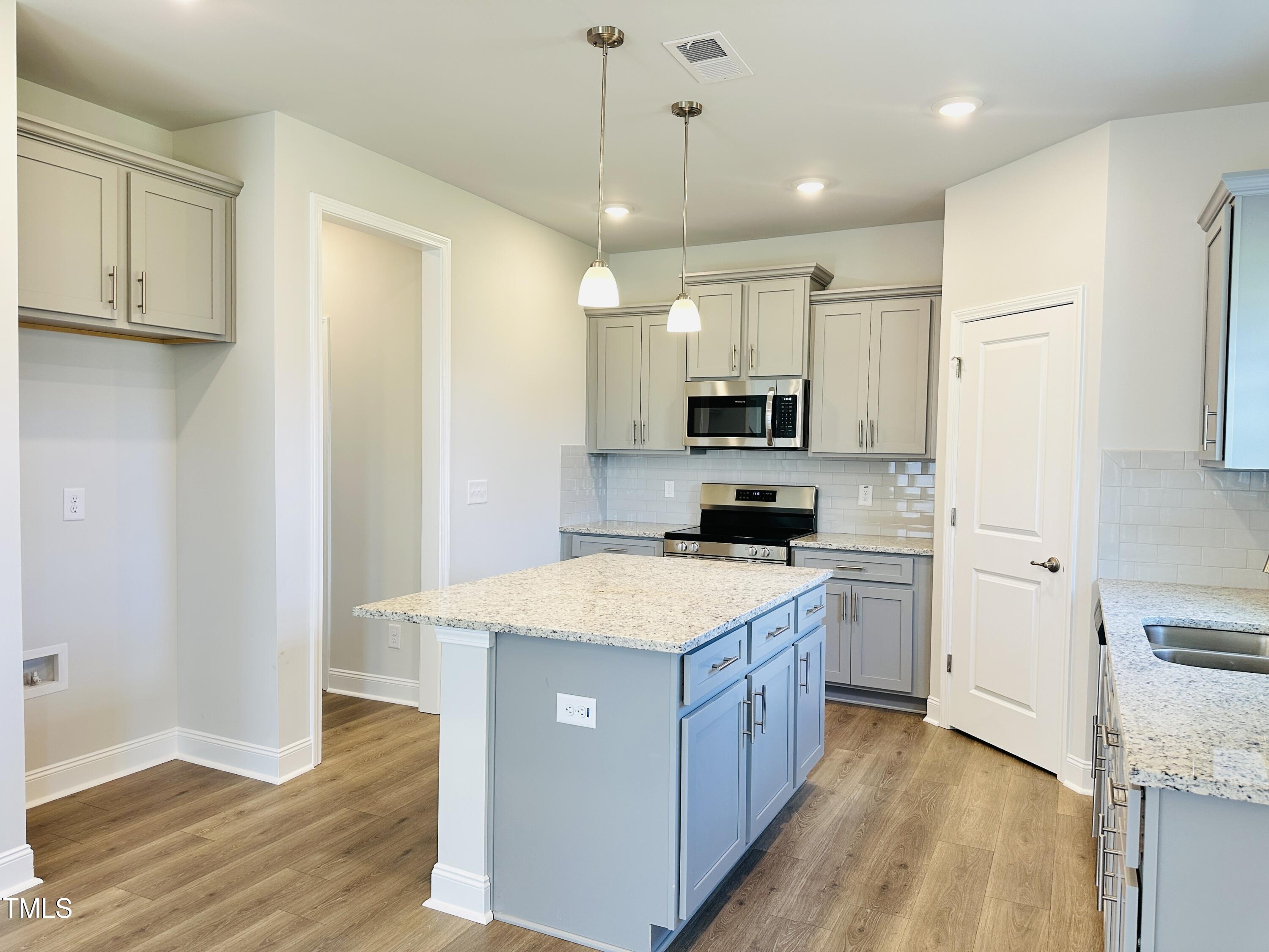 3982 Fletcher Road Bailey, NC 27807 - Photo 6 of 28 a large kitchen with stainless steel appliances granite countertop a stove a sink a refrigerator and white cabinets with wooden floor