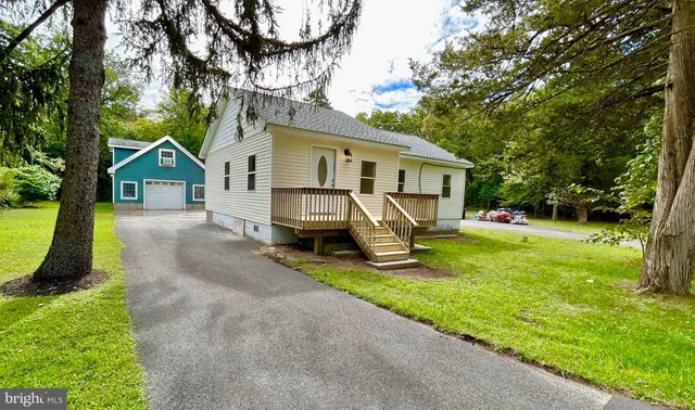 a view of house with a yard and large trees