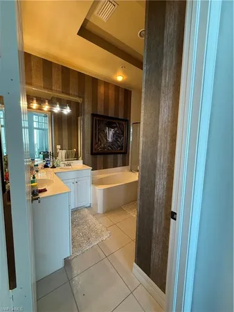 a bathroom with a tub a sink and a large mirror