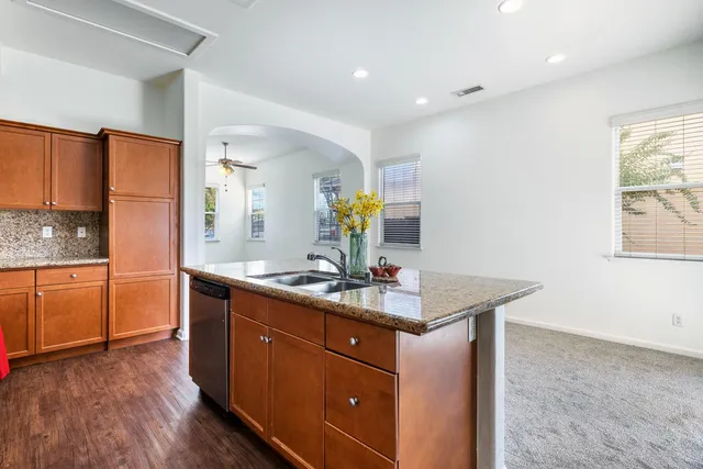a kitchen with kitchen island granite countertop a sink cabinets and wooden floor