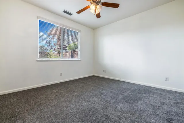an empty room with a window and a fan