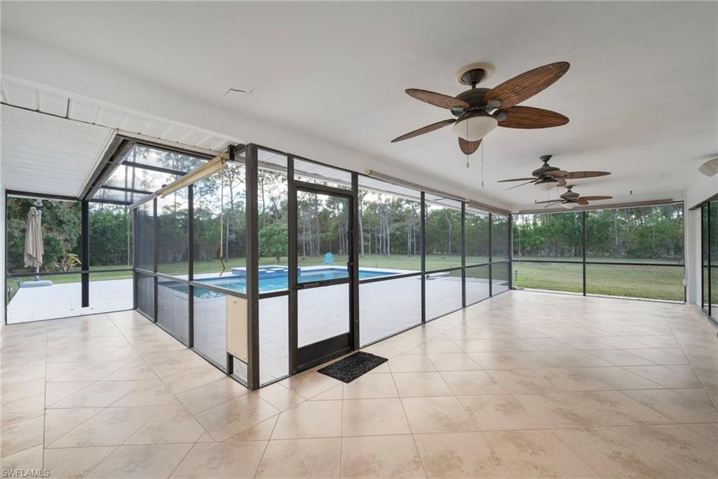6440 Sable Ridge Lane Naples, FL 34109 - Photo 14 of 20 Unfurnished sunroom with a ceiling fan, view of wooded area, and a swimming pool