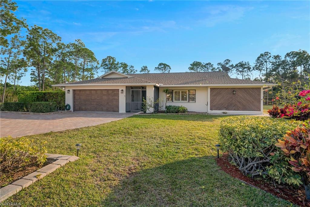 6440 Sable Ridge Lane Naples, FL 34109 - Photo 2 of 20 Ranch-style house featuring a front yard, decorative driveway, stucco siding, an attached garage, and roof with shingles
