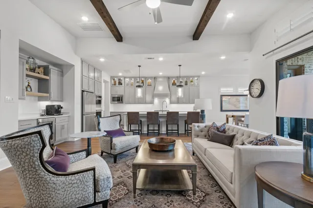 a large white kitchen with kitchen island a stove a sink a oven and a dining table with wooden floor