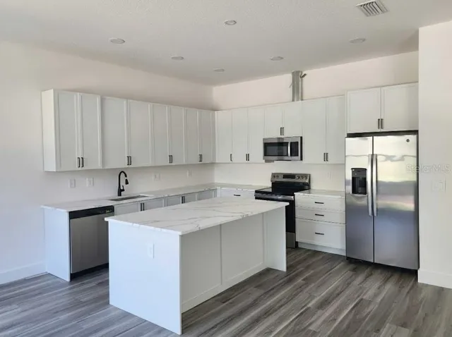 a kitchen with stainless steel appliances granite countertop a stove a sink and a refrigerator