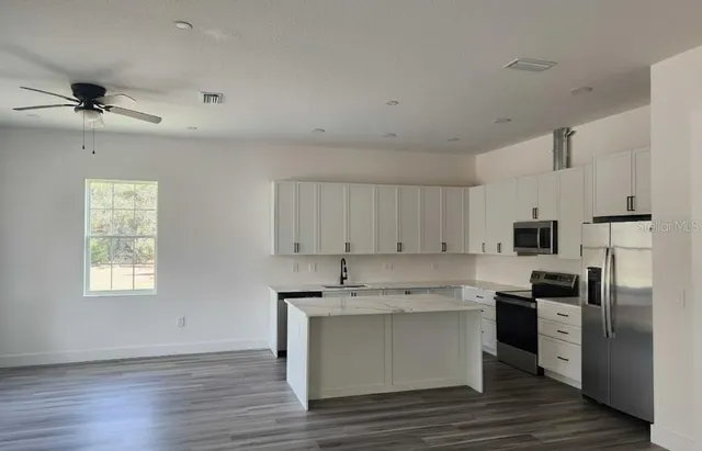 a kitchen with stainless steel appliances granite countertop a stove a sink dishwasher and a refrigerator with wooden floor