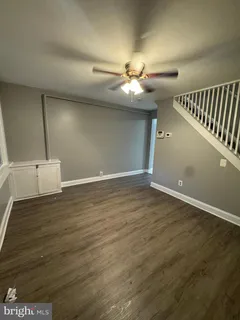 an empty room with wooden floor fan and windows