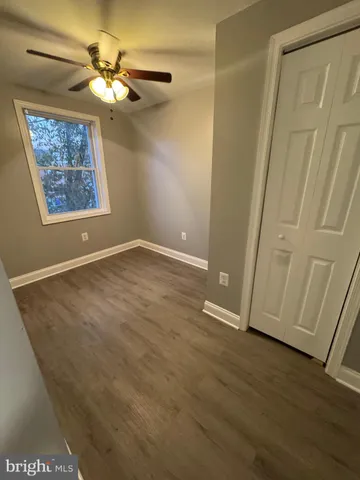 an empty room with wooden floor chandelier fan and windows