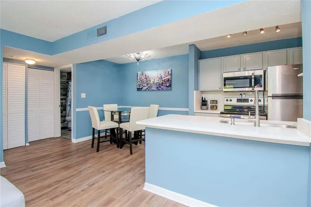 a kitchen with stainless steel appliances a dining table chairs and wooden floor