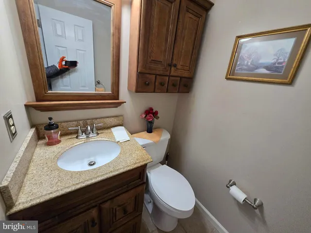 a bathroom with a granite countertop toilet sink and mirror