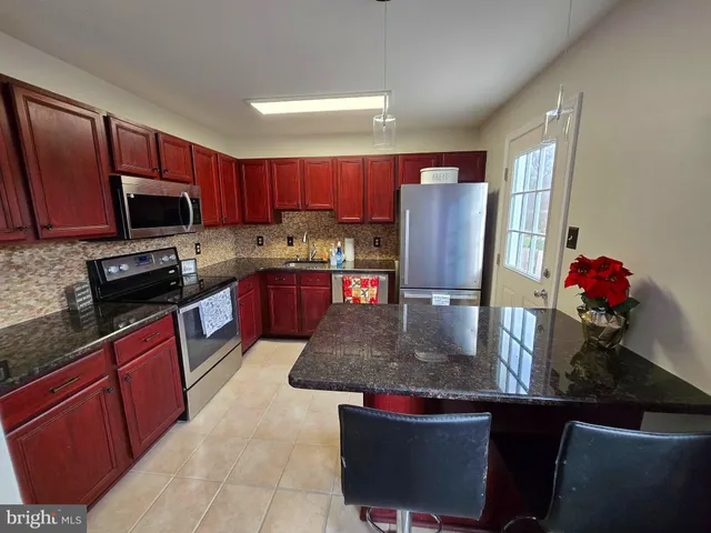 a kitchen with kitchen island granite countertop a sink dishwasher stove and cabinets