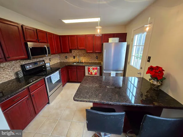 a kitchen with stainless steel appliances granite countertop a stove refrigerator sink and cabinets