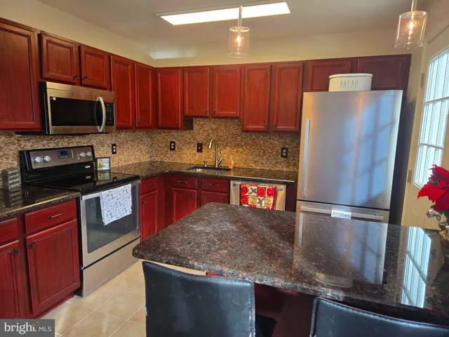 a kitchen with stainless steel appliances granite countertop a refrigerator a stove a sink and a microwave