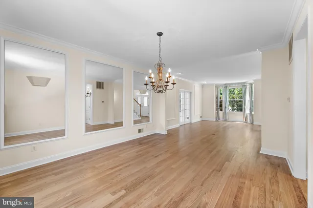 a view of a room with wooden floor chandelier and windows