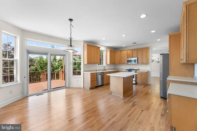 a large kitchen with a large counter top a sink stainless steel appliances and cabinets