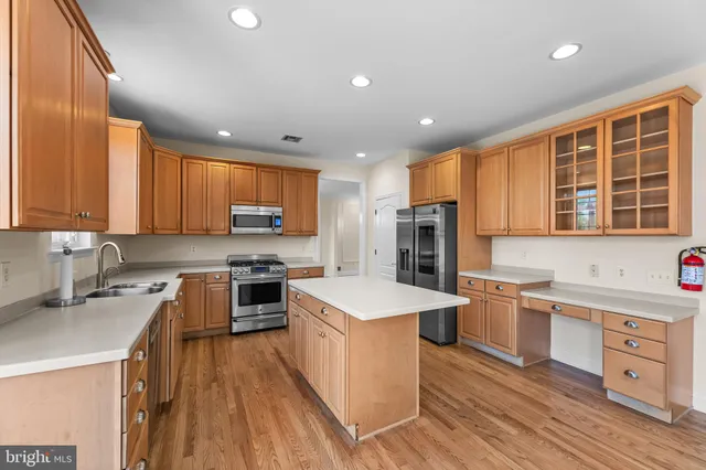 a kitchen with stainless steel appliances granite countertop a stove top oven a sink dishwasher a refrigerator and white cabinets with wooden floor