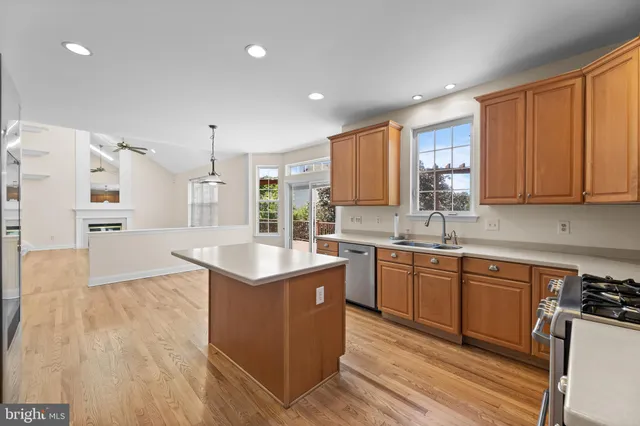 a kitchen with stainless steel appliances granite countertop a stove a sink dishwasher and a refrigerator with wooden floor