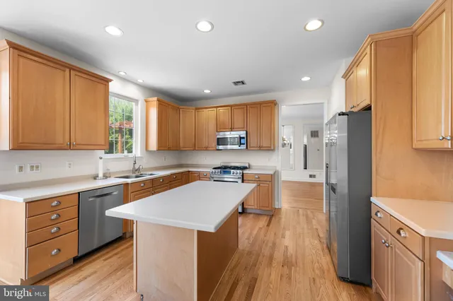 a kitchen with a refrigerator a sink a stove a microwave a center island and cabinets