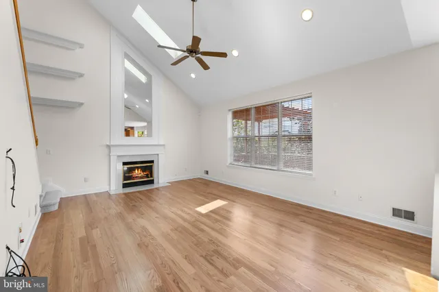 an empty room with windows fireplace and ceiling fan