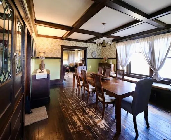 a dining room with wooden floor a chandelier a glass table and chairs