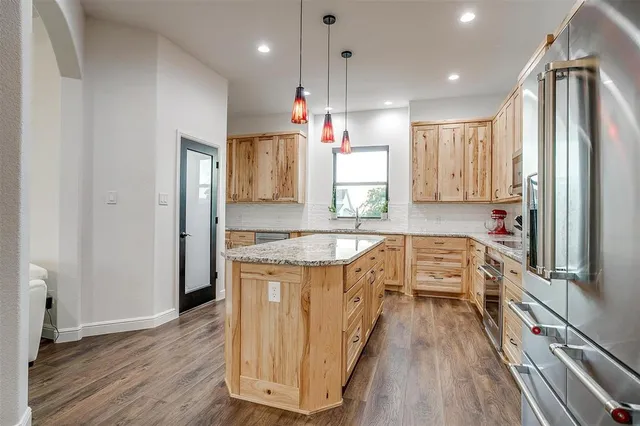 a kitchen with stainless steel appliances granite countertop a refrigerator a sink dishwasher a stove and white countertops with wooden floor