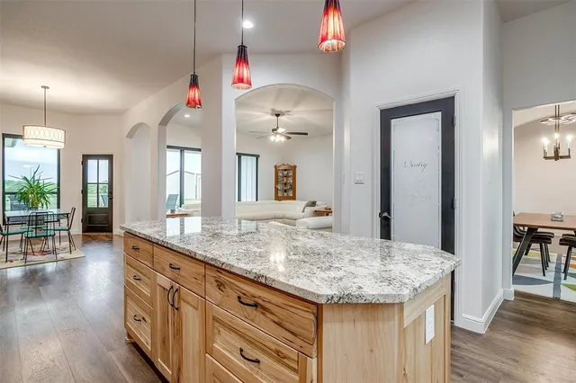 a kitchen with granite countertop hallway and wooden floor