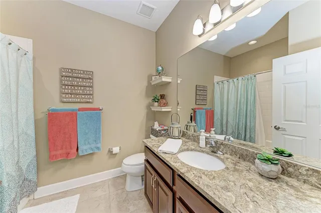 a bathroom with a granite countertop sink a large mirror and a toilet
