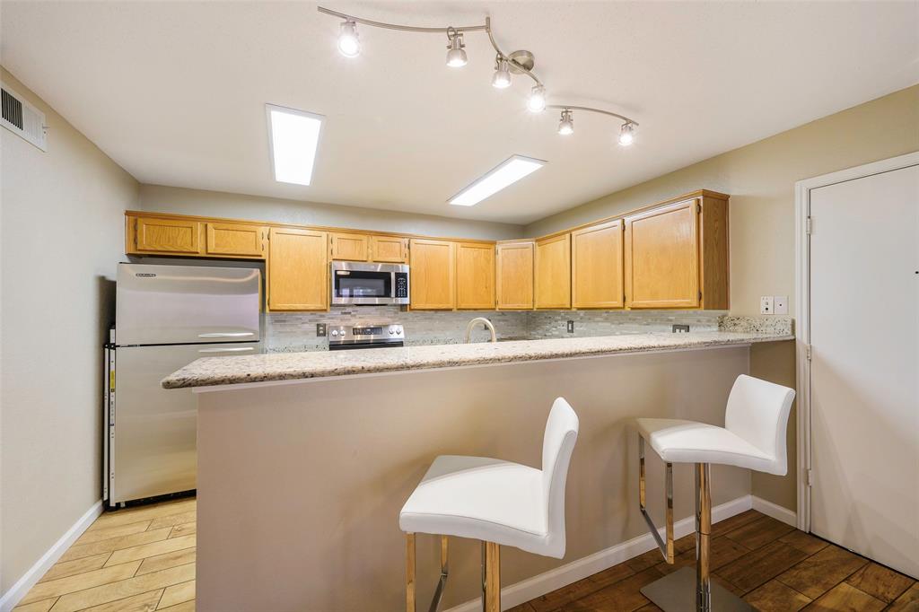 2903 Fort Point Lane Carrollton, TX 75007 - Photo 11 of 27 a kitchen with stainless steel appliances granite countertop a table chairs in it and wooden floors