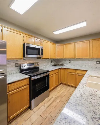 a kitchen with stainless steel appliances granite countertop a stove a sink and a microwave