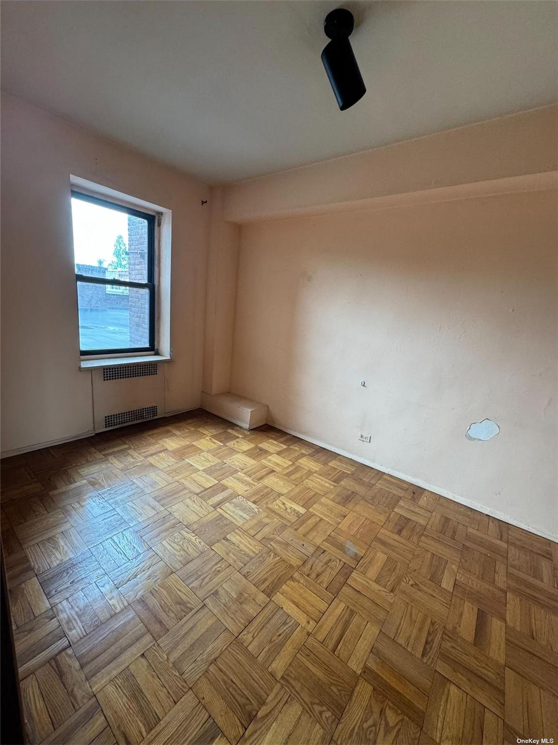 67-76 Booth Street, Unit 1G Queens, NY 11375 - Photo 5 of 15 an empty room with wooden floor and windows