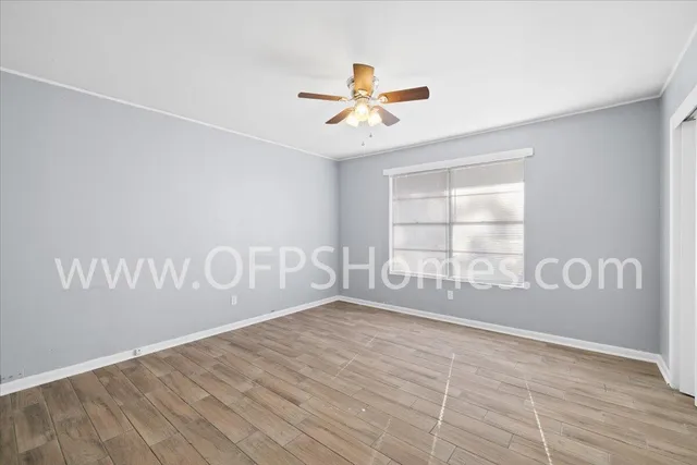 a view of empty room with window and ceiling fan
