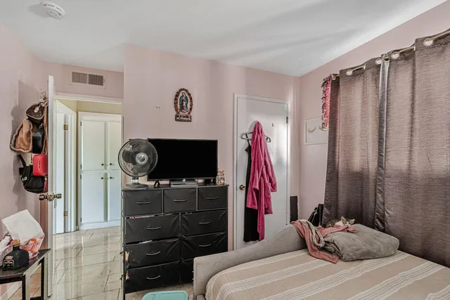 a bedroom with a bed and a flat tv screen on the dresser