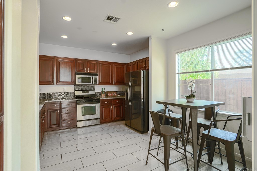629 Sumner Way, Unit 2 Oceanside, CA 92058 - Photo 6 of 21 a kitchen with stainless steel appliances granite countertop a stove top oven a sink dishwasher a dining table and chairs