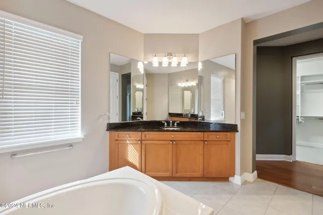 a spacious bathroom with a granite countertop sink and a mirror