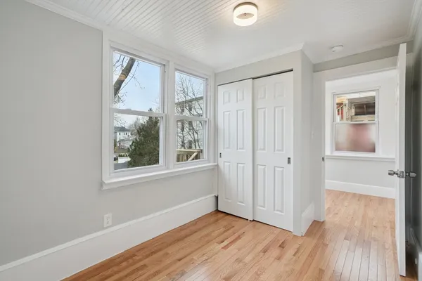 a view of an empty room with wooden floor and a window