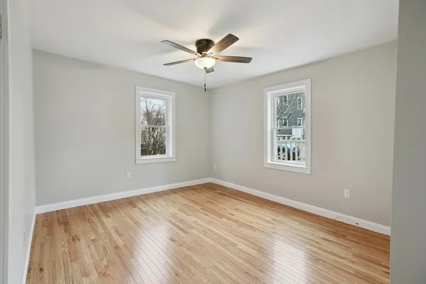 a view of empty room with wooden floor and fan