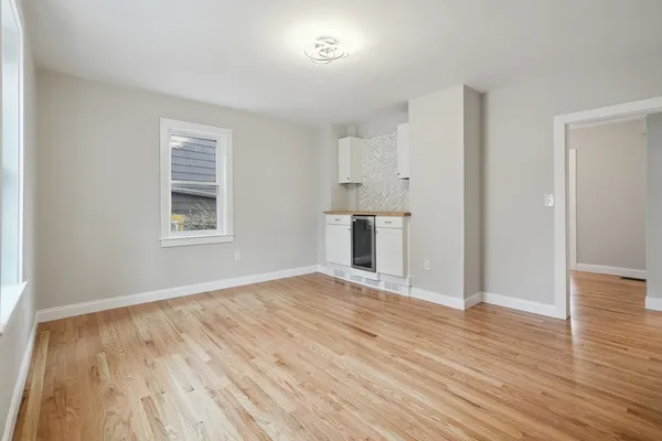 an empty room with wooden floor cabinet and windows