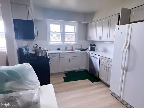 a kitchen with stainless steel appliances a sink a stove a refrigerator cabinets and a window