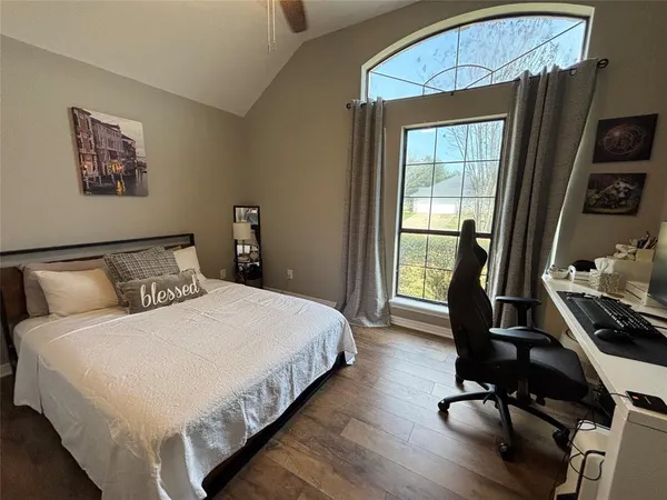 a bedroom with a bed a flat screen tv and a window