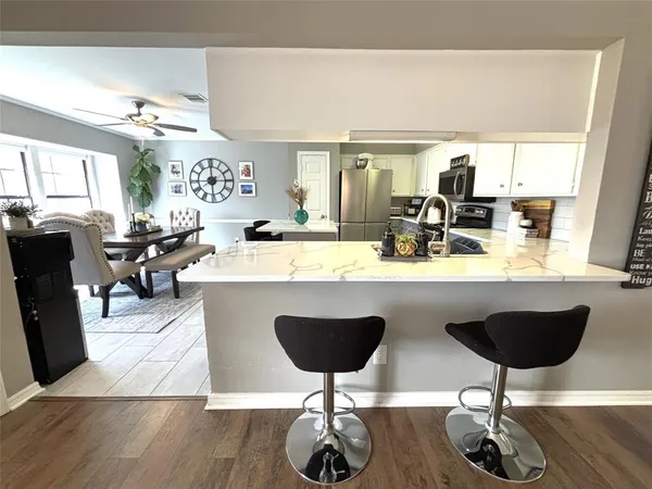 a kitchen with stainless steel appliances granite countertop a table chairs sink and wooden floor