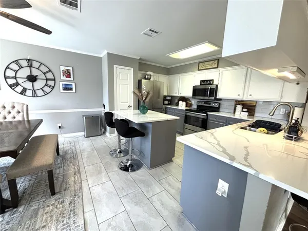 a view of kitchen with stainless steel appliances kitchen island granite countertop a sink dishwasher a stove a dining table and chairs with wooden floor