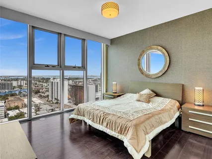 a bedroom with a bed lamp and a large window