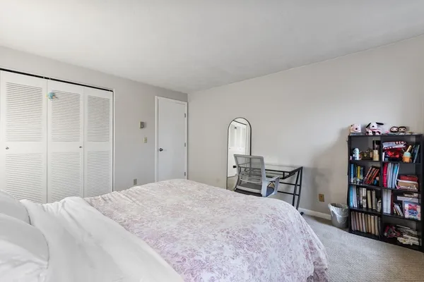 a bedroom with a bed a table and a book shelf