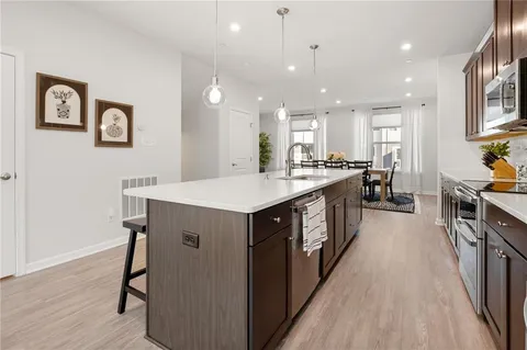 a kitchen with a stove a sink a refrigerator and chairs